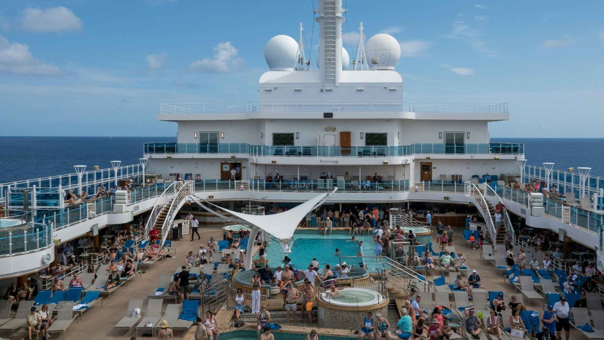 Crowded cruise ship deck with passengers engaging in multiple floors.